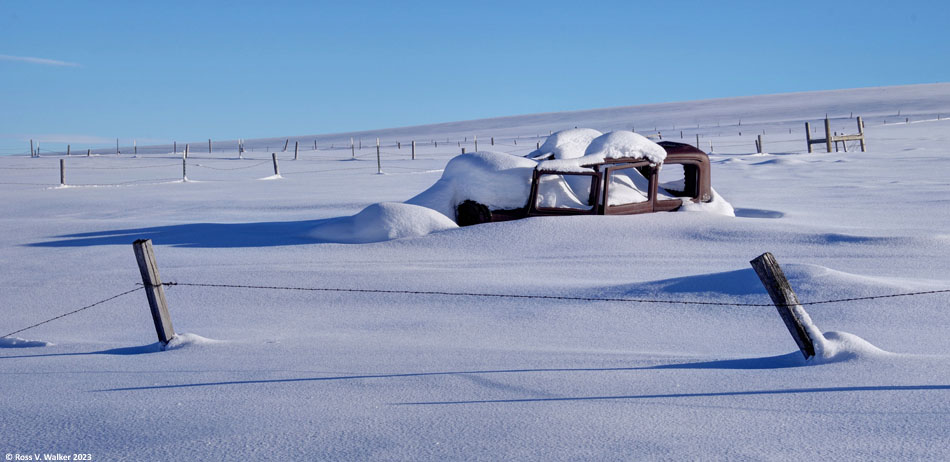 A rusty sedan is buried in snow in Sharon, Idaho